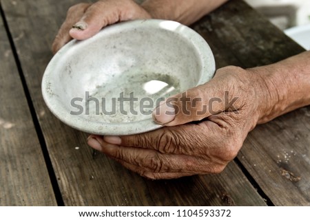 The poor old man's hands hold an empty bowl. The concept of hunger or poverty. Selective focus. Poverty in retirement. Alms