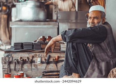 Poor old sad Pakistani Pathan shoe man cobbler on the local streets of Pakistan with his hand made leather shoes and repair tools in his street shop - Powered by Shutterstock