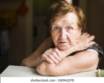 Poor old woman in her home, looking into the camera.