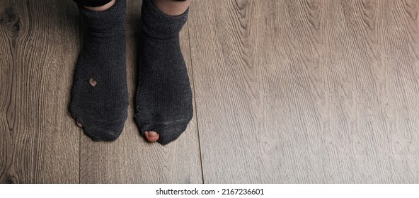Poor person in shabby socks on wooden floor, closeup view with space for text. Banner design - Shutterstock ID 2167236601