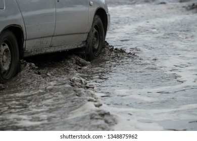 Poor road condotions - car wheel in melting show puddle. - Shutterstock ID 1348875962