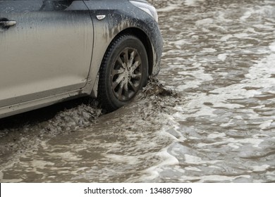 Poor road condotions - car wheel in melting show puddle. - Shutterstock ID 1348875980