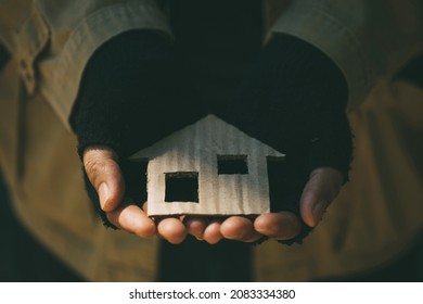  Poor tired depressed hungry homeless man holding a cardboard house. nostalgia and hope concept. - Shutterstock ID 2083334380