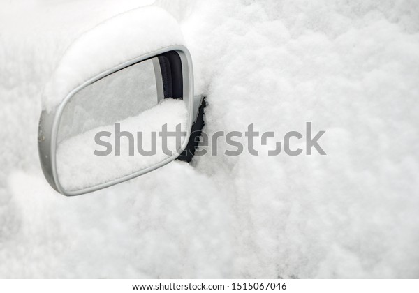 Poor visibility on the road. Car side mirror. Car\
under the snow. Automobile covered with white snow. Bad weather\
conditions. Winter travel background. Temperature below zero.\
Concept, idea