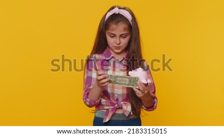 Poor young preteen child girl kid insufficient amount of money, holding piggybank and one dollar banknote at home. Financial crisis. Bankruptcy. Poverty and destitution. Little toddler children alone