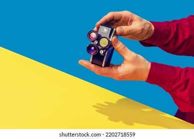 Pop art photography. Colorful image of retro photo camera on bright yellow tablecloth isolated over blue background. Concept of art culture, vintage things, mix old and modernity. Copy space for ad