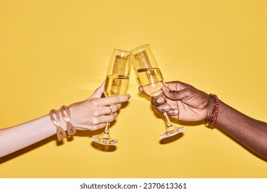 Pop color closeup of two hands clinking tall champagne glasses against vibrant yellow background - Powered by Shutterstock