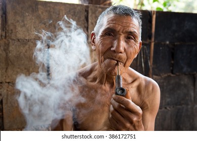 POP PRA, TAK, THAILAND - MARCH 05, 2016 : Unidentified elderly Akha man is smoking traditional tobacco pipe at KM48, Pop Pra, Tak, Thailand.