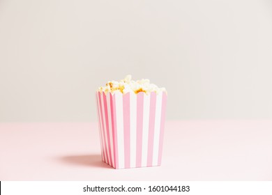 Popcorn Bag With White And Pink Stripes At The Light Neutral Backdrop. Empty Minimalistic Background. Romantic Movie Night And Snack Concept. Horizontal