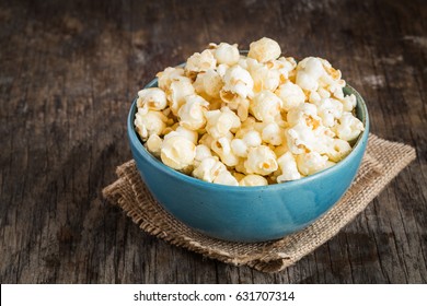 popcorn in a blue bowl on a dark wooden background