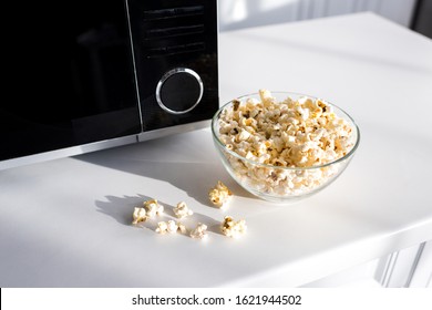 Popcorn In Bowl Near Microwave On Table In Kitchen