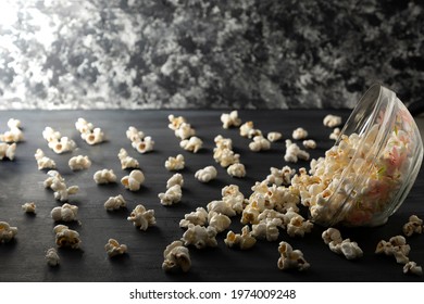 Popcorn Bowl Turned Over On A Black Wooden Table. Popcorn Scattered On The Table