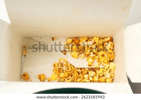 Popcorn box with kernels of popcorn inside, remaining popcorn
