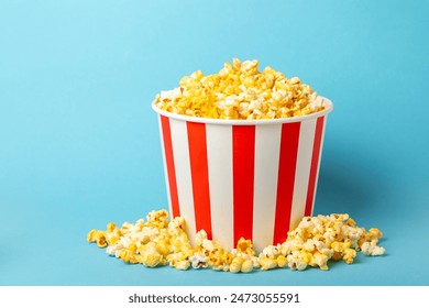 Popcorn box. Red and white striped buckets of popcorn on a blue background. Cinema and entertainment concept. Movie night with popcorn. Cheesy popcorn. Delicious appetizer, snack. Place for text. - Powered by Shutterstock