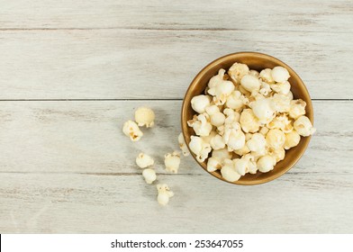 Popcorn In Brown Bowl On White Wooden Table.