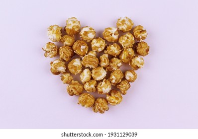 Popcorn in caramel heart symbol on white background