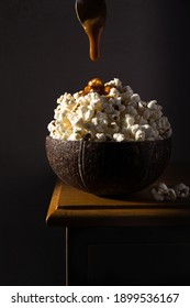 Popcorn In Coconut Bowl With Caramel Drizzle. Pour Dark Food Photography