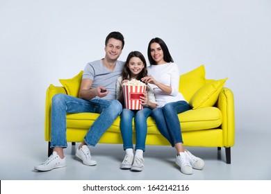 Popcorn Lovers. Cheerful Family Of Three Eating Popcorn And Watching TV Together At Home.