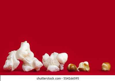 Popcorn over vibrant red background.  Closeup of popped and unpopped corn kernels. Side view. Very large file.