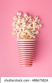 Popcorn in paper cup on colorful background.