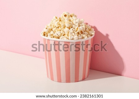Popcorn in pink paper bag on pink background