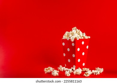 Popcorn in a red bag with white polka dots on a red background. Front view, copy space. - Powered by Shutterstock