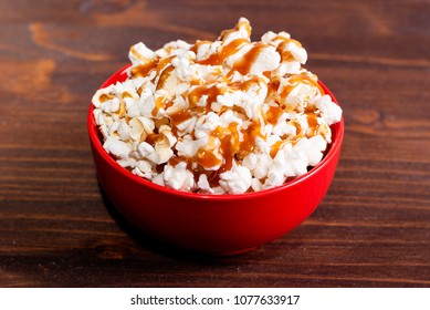 Popcorn In A Red Bowl Of Poured Caramel, On A Dark Table