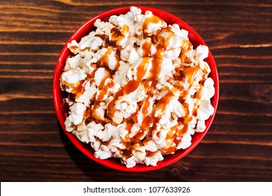 Popcorn In A Red Bowl Of Poured Caramel, On A Dark Table