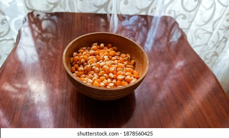 Popcorn seed on wooden background. Raw popcorn background texture. Background of bulk of yellow shiny corn grains.