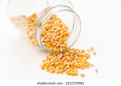 Popcorn Seeds Spilled From Transparent Glass Jar On White Background