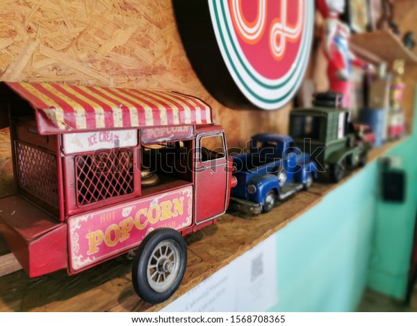 Red​ Popcorn selling cart model car toy on a display as\
collection together with other items,​ close up of Colorful\
Collectable Car toy at Mee Restaurant, Vientiane, Lao PDR, 22nd\
November 2019 