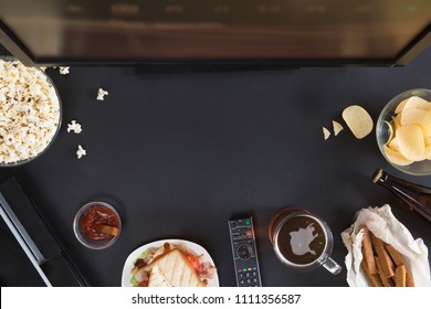 Popcorn, Snack And A Remote Control For The TV, Top View And Flat Lay On Black Background