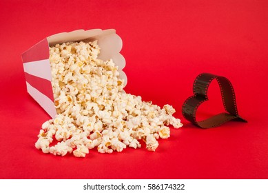 Popcorn spilled on blue background and film in heart form