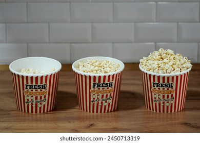 Popcorn in a striped box on a wooden table. Selective focus. Delicious fast food - Powered by Shutterstock