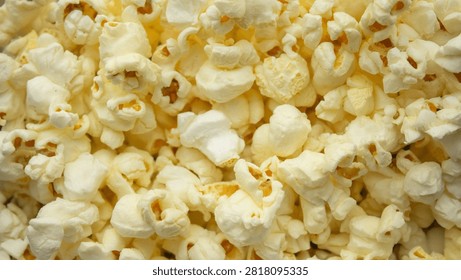 Popcorn texture background close up. Macro shot of fresh butter popcorn filling the frame, perfect for cinema, movie night, and snack food commercial concepts.