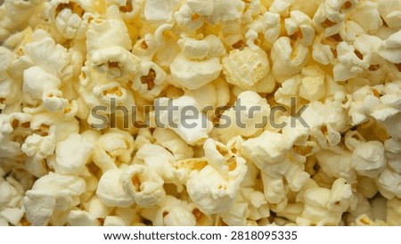 Popcorn texture background close up. Macro shot of fresh butter popcorn filling the frame, perfect for cinema, movie night, and snack food commercial concepts.