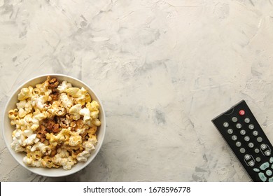 Popcorn And Tv Remote Control On A Light Concrete Table. Concept Of Watching A Movie Or Video At Home. Top View