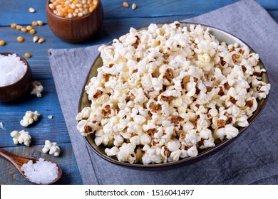 Popcorn, unpopped kernels and sea salt on blue wooden table