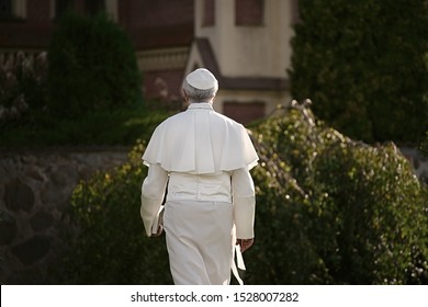 Pope walks at the end of the day in the garden. Back view                               