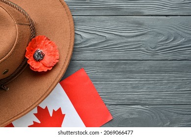 Poppy flower with hat and flag of Canada on wooden background. Remembrance Day - Powered by Shutterstock