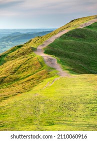 Popular beauty spot and landmark,lsoon after dawn,ow angled summer sunlight,clipping the ridges of the Malvern Hills,textured lush,green grass covered,curved rolling slopes and detailed ridges.