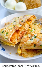 Popular Chinese Breakfast (Jian Bing) Egg Wrap Stuffed With Pork And Shredded Potato. Boiled Eggs Blurred At Background.