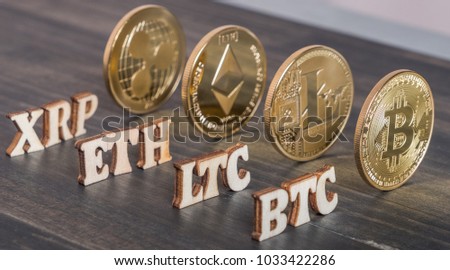 Popular cryptocurrency bitcoin, litecoin, ripplecoin and ethereum with text on wooden background.