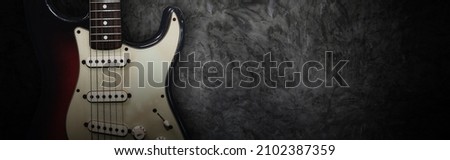 Popular electric guitar : Two tone rock and roll style red-black electric guitar leaning against blank grunge plaster background with copy space : Selection focus.