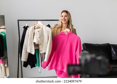 Popular fashion blogger recording video review of new clothes collection at home, showing beautiful dress to camera. Happy lady making online wardrobe management and styling course - Powered by Shutterstock