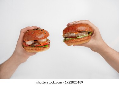 Popular food review, advertising of delicious meal, delivery online order at work or home. Hands of modern blogger holds burgers with meat and seafood, isolated on white background, copy space