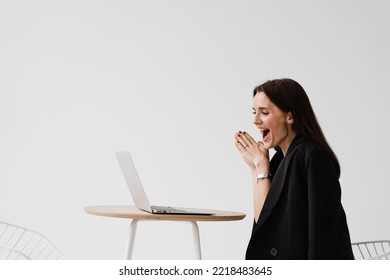 Popular Girl Blogger Looks At Statistics Of Her Channel And Enjoys Lot Of Views Of Her Videos. Happy Woman With Laptop Smiles And Rejoices On White Background