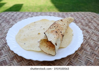 Popular Indian Savoury Snack Eaten With Lunch Dinner Or Just Snacks. Papad Or Pappadoms. Both Roasted And Deep Fried Papads Served In White Plate