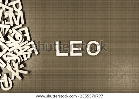 Popular and modern baby boy fashion name LEO in wooden English language capital letters spilling from a pile of letters on a green background in sepia