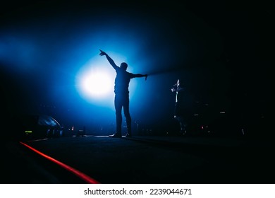 Popular singer on stage in front of crowd on scene in night club. Bright stage lighting. Silhouette of a dancing person. - Shutterstock ID 2239044671